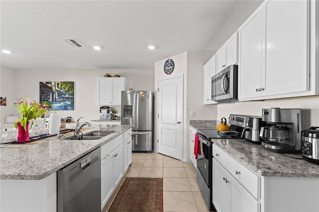 kitchen with visible vents, white cabinets, stainless steel appliances, a sink, and light tile patterned flooring