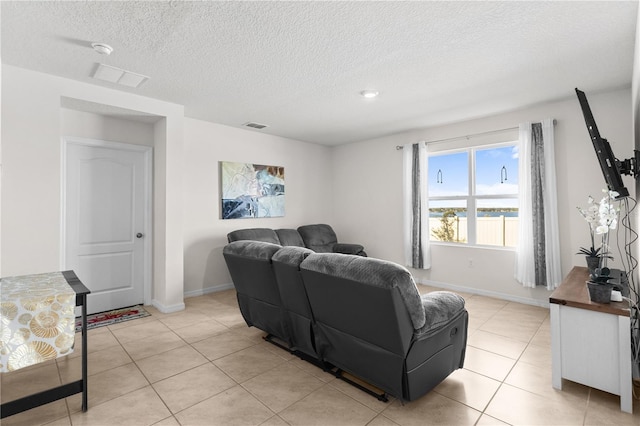 living room featuring baseboards, visible vents, a textured ceiling, and light tile patterned flooring