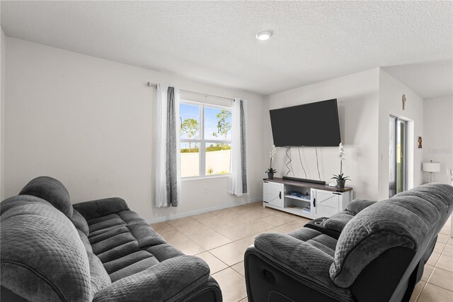 living area featuring light tile patterned flooring, a textured ceiling, and baseboards