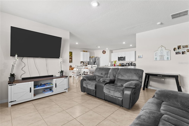 living area featuring light tile patterned floors, visible vents, a textured ceiling, and recessed lighting