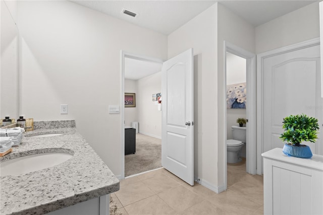 bathroom featuring visible vents, a sink, toilet, and double vanity