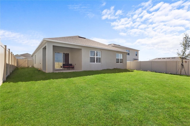 back of property with a fenced backyard, a lawn, and stucco siding