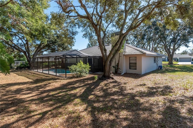 back of property with a lawn and glass enclosure