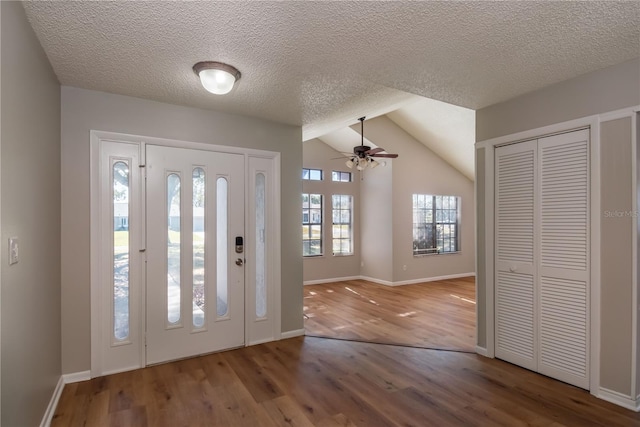 foyer with wood-type flooring, a textured ceiling, ceiling fan, and lofted ceiling