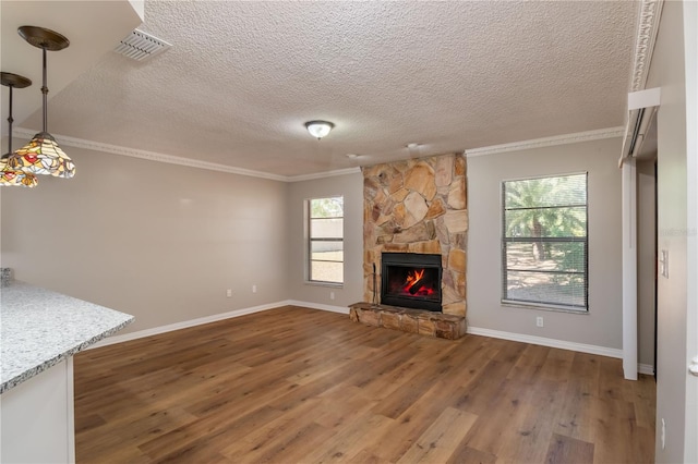 unfurnished living room with a stone fireplace, dark wood-type flooring, a textured ceiling, and ornamental molding