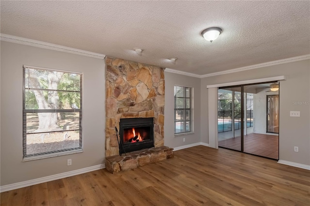 unfurnished living room with a stone fireplace, crown molding, wood-type flooring, and a textured ceiling