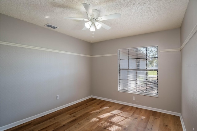 empty room featuring ceiling fan, wood-type flooring, and a textured ceiling