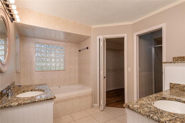 bathroom with tile patterned flooring, vanity, crown molding, and tiled tub