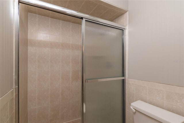 bathroom featuring an enclosed shower, toilet, and tile walls