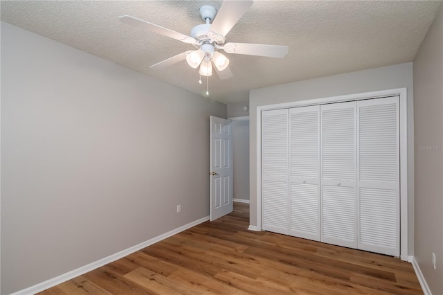 unfurnished bedroom featuring ceiling fan, a closet, a textured ceiling, and hardwood / wood-style flooring