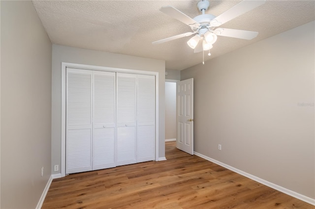 unfurnished bedroom with hardwood / wood-style flooring, ceiling fan, a textured ceiling, and a closet