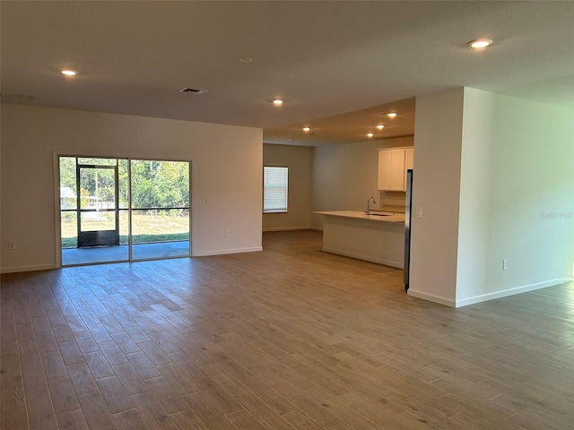 unfurnished living room featuring light hardwood / wood-style floors and sink