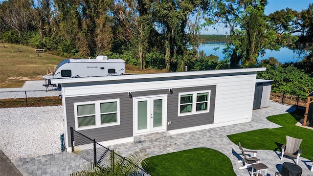 exterior space featuring french doors, a water view, and a patio area