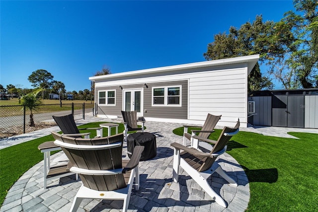 exterior space featuring a lawn, french doors, a fire pit, a shed, and a patio area