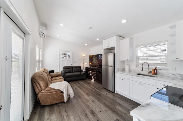 kitchen featuring a healthy amount of sunlight, sink, white cabinets, stainless steel refrigerator, and lofted ceiling