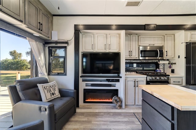 kitchen featuring decorative backsplash, black gas range oven, and light hardwood / wood-style floors