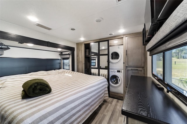 bedroom featuring hardwood / wood-style floors and stacked washer / dryer