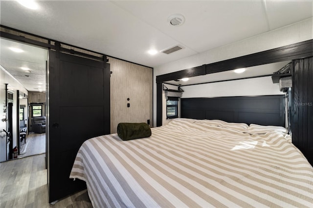 bedroom featuring a barn door and wood-type flooring