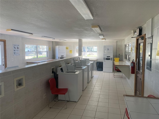 kitchen with stacked washer / dryer, a healthy amount of sunlight, and tile walls