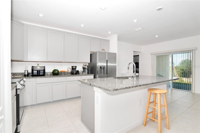 4313 SW 106th Pl, Ocala, FL 34476 - kitchen featuring appliances with stainless steel finishes, a sink, light stone countertops, light tile patterned floors, and a breakfast bar