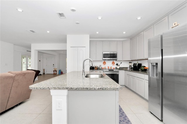 kitchen featuring light stone countertops, a kitchen island with sink, sink, and stainless steel appliances