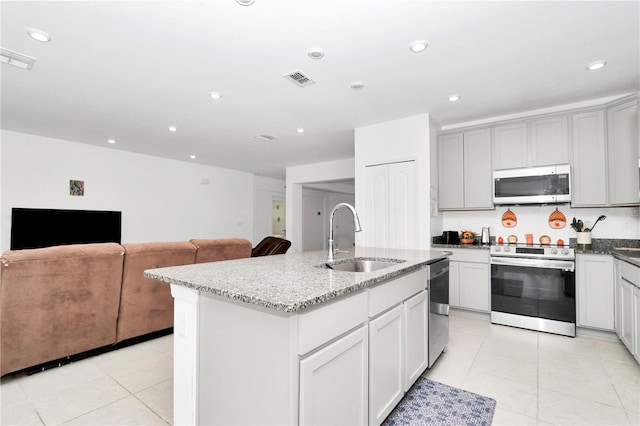 4313 SW 106th Pl, Ocala, FL 34476 - kitchen with stainless steel appliances, a sink, light tile patterned floors, light stone countertops, and a center island with sink