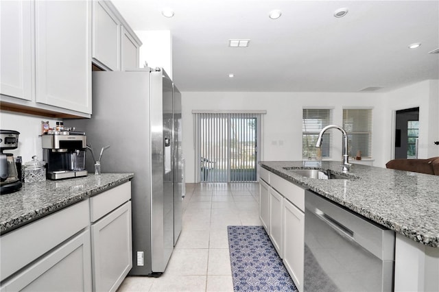 kitchen with light stone countertops, stainless steel appliances, white cabinetry, and sink