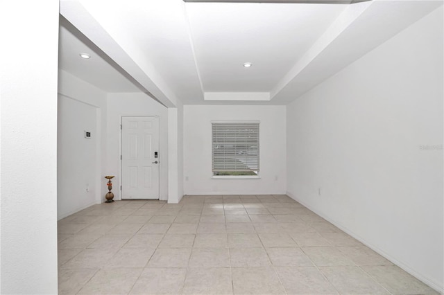 empty room with a raised ceiling and light tile patterned floors