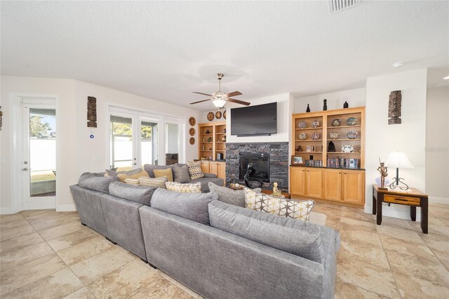 living room with a textured ceiling, built in features, and ceiling fan