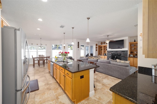 kitchen featuring dark stone countertops, sink, a kitchen island with sink, and appliances with stainless steel finishes