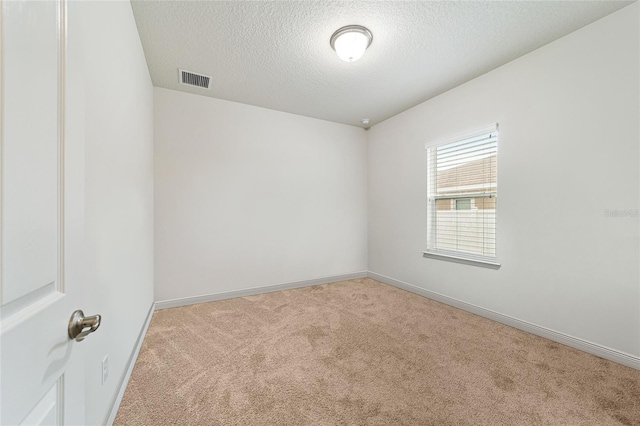 empty room with a textured ceiling and light colored carpet