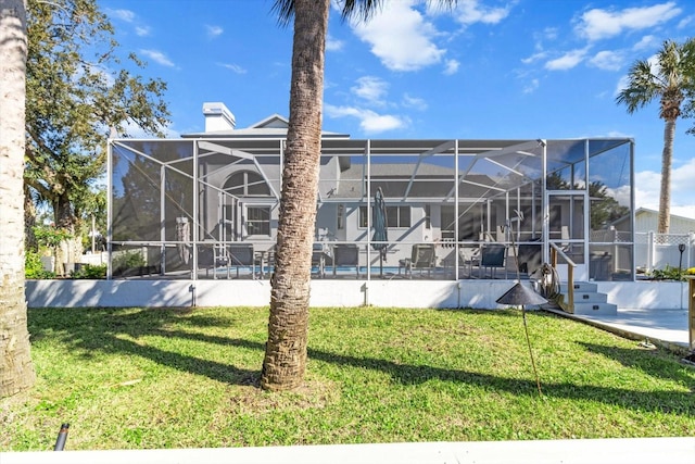 rear view of house with glass enclosure and a yard