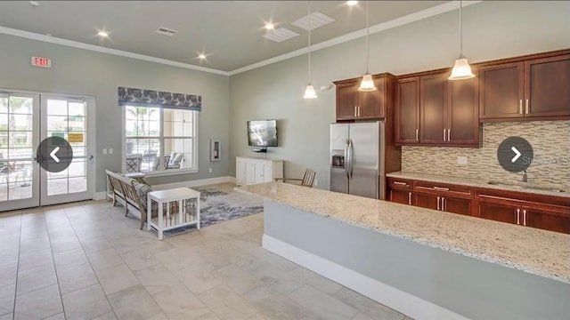 kitchen featuring light stone countertops, stainless steel refrigerator with ice dispenser, tasteful backsplash, crown molding, and hanging light fixtures