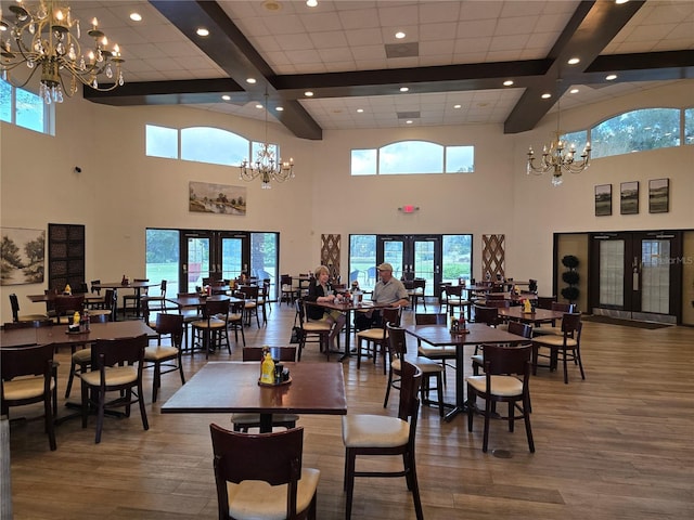 dining area with french doors, wood-type flooring, an inviting chandelier, and beamed ceiling