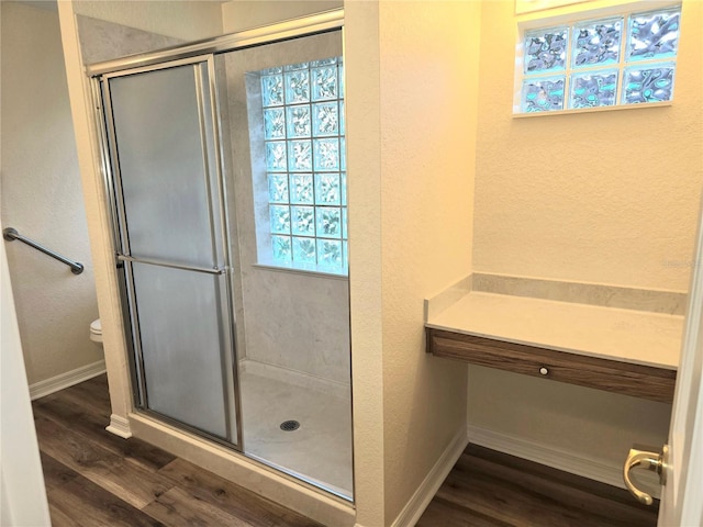 bathroom featuring hardwood / wood-style flooring, toilet, and a shower with door