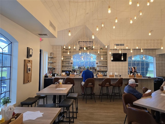 bar with wood-type flooring and lofted ceiling