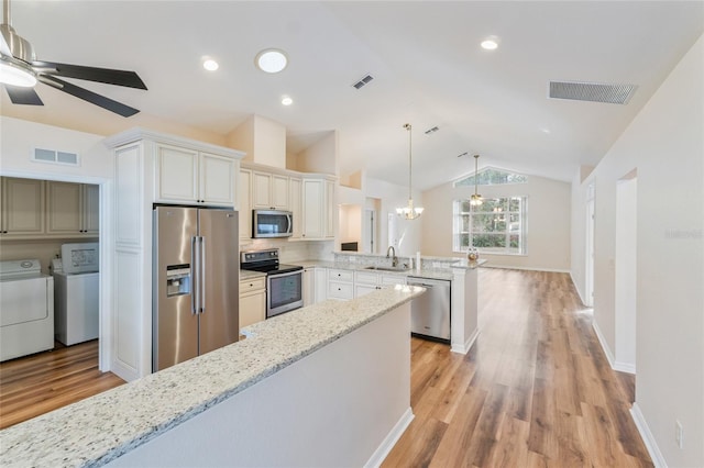 kitchen with appliances with stainless steel finishes, pendant lighting, white cabinets, kitchen peninsula, and washer and clothes dryer