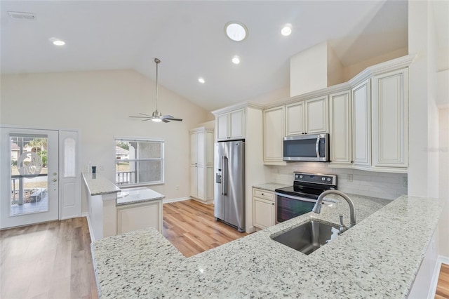 kitchen with appliances with stainless steel finishes, sink, light hardwood / wood-style floors, kitchen peninsula, and light stone countertops