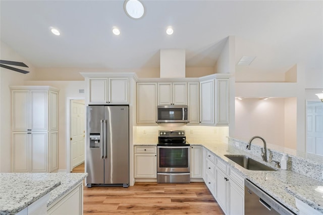 kitchen with sink, backsplash, stainless steel appliances, light stone countertops, and light hardwood / wood-style flooring