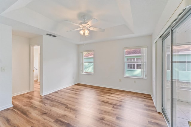 unfurnished room with a tray ceiling, light hardwood / wood-style flooring, and ceiling fan