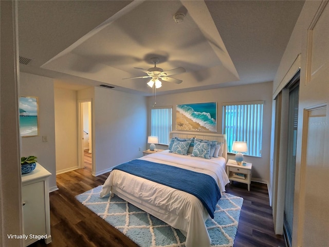 bedroom featuring ceiling fan, dark hardwood / wood-style floors, and a raised ceiling