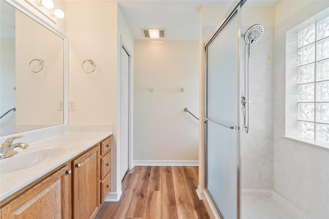 bathroom with vanity, wood-type flooring, a shower with shower door, and a healthy amount of sunlight