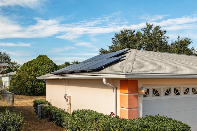 view of property exterior with solar panels, a garage, and cooling unit