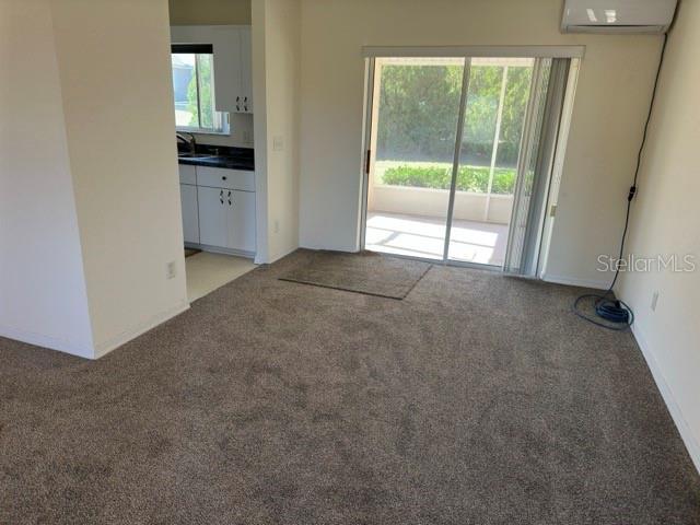 carpeted empty room with sink and a wall mounted AC