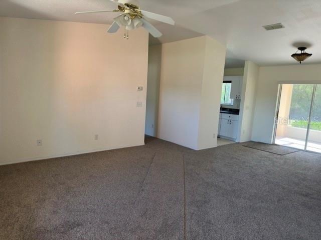 unfurnished living room featuring carpet floors and ceiling fan