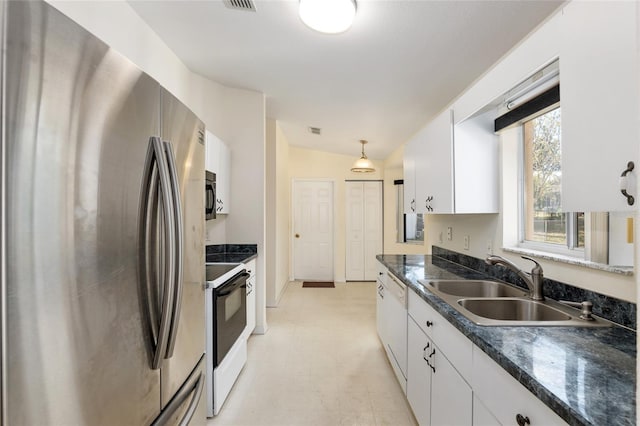 kitchen featuring lofted ceiling, sink, appliances with stainless steel finishes, decorative light fixtures, and white cabinetry