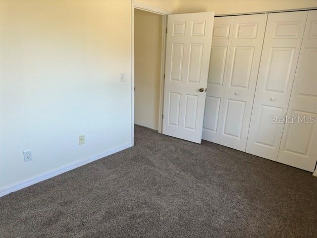 unfurnished bedroom with a closet and dark carpet