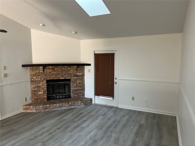 unfurnished living room with a fireplace, dark hardwood / wood-style flooring, and a skylight