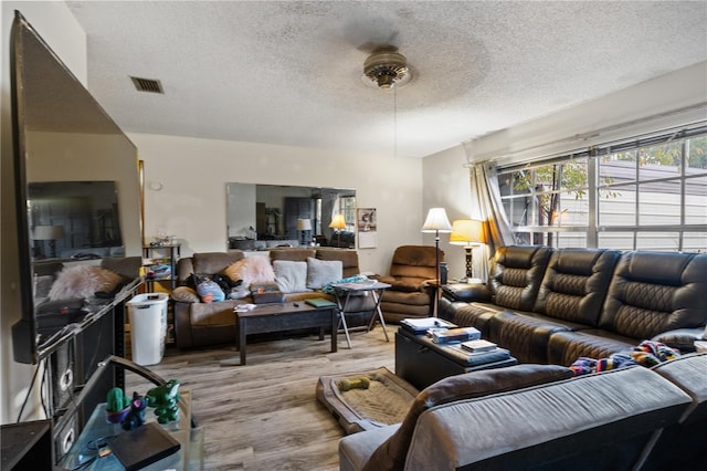 living room with a textured ceiling, light hardwood / wood-style floors, and ceiling fan