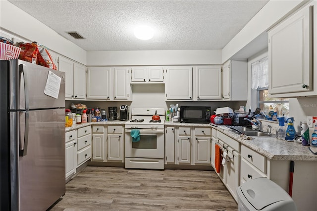 kitchen featuring white cabinetry, white range with gas cooktop, and stainless steel fridge